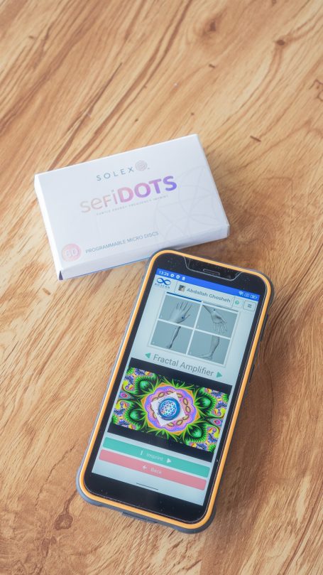 Smartphone mit buntem Bildschirm und einer Packung mit dem Namen "DOTS" daneben.